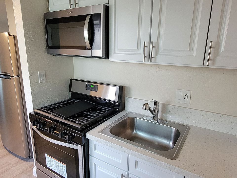 Kitchen with gas range, microwave and white cabinets at Orlando Woods Apartments in El Cajon, California.