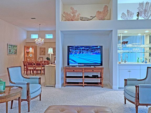 This view of the living room show the entertainment and wet bar, nautical decorations above, and a partial view of the dining room on the left.