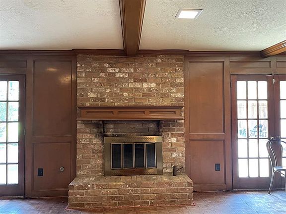 Den with fireplace, parque flooring and french doors leading to backyard.