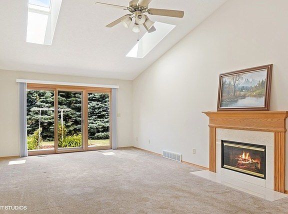 Vaulted ceiling, new sky lights, ceiling fan, and sliding glass door to the patio with private tree-