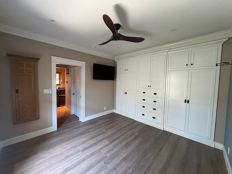 Bedroom ironing board in oak cabinet, TV and wall of closets
