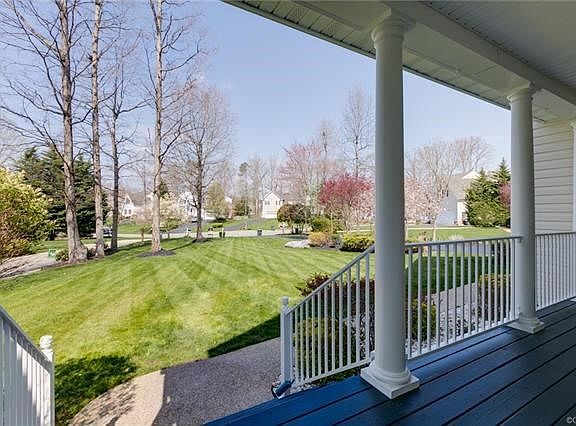 Inviting front porch overlooks long green lawn and cul-de-sac