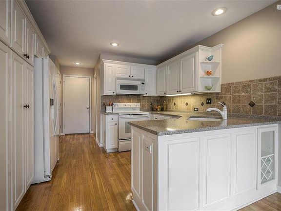 The Updated Kitchen has a vast amount of custom cabinets, hardwood floors, granite counter tops, tile back splash, and all the appliances stay with the home including the refrigerator.  The door to the back leads to the attached, 2 car garage, and there is another door leading to the laundry room.