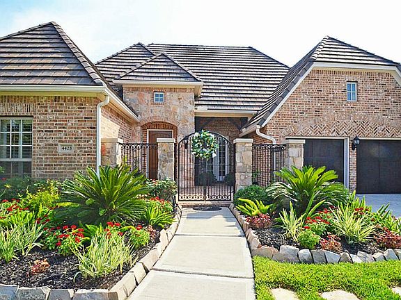 THIS LUSHLY LANDSCAPED BRICK&STONE HOME IS ENHANCED WITH TILE ROOF,STAINED GARAGE DOORS&CUSTOM IRON GATES!