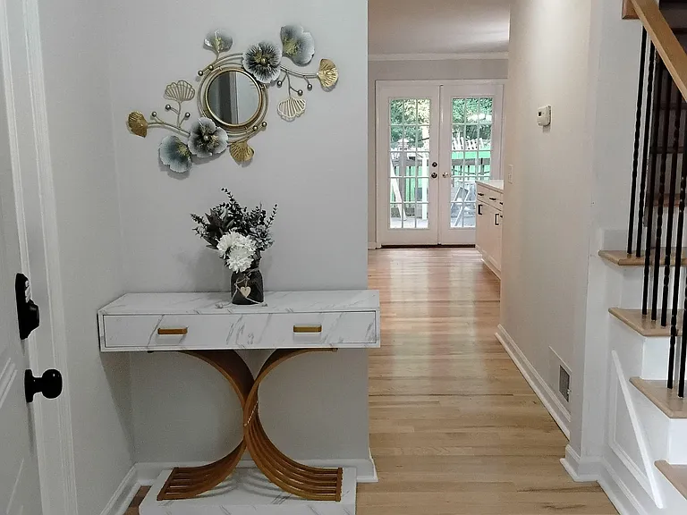 Welcoming entry hallway with hardwood floors, a console table, and direct access to the rear patio through French doors.