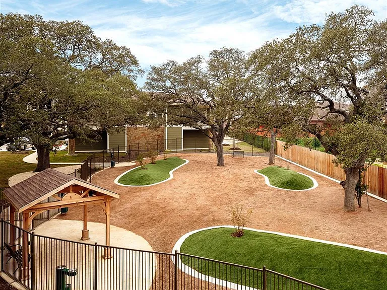 Aerial view of fenced in dog park with shaded gazebo and shade trees