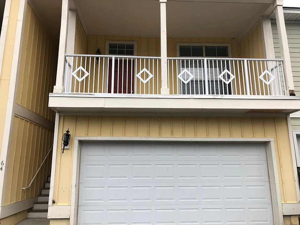 main entrance and 2 car garage with living room balcony