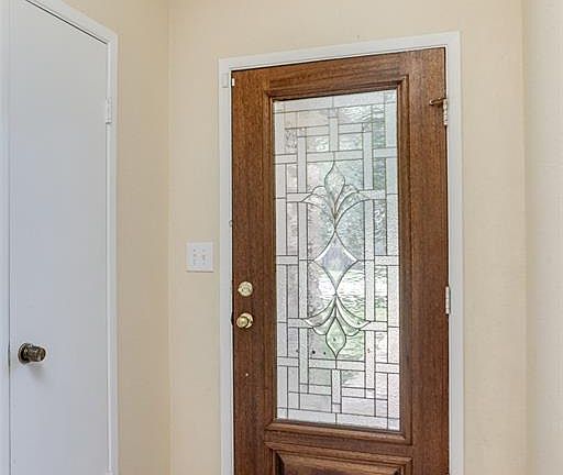 A step into the foyer reveals a spacious greeting area with a coat closet conveniently located to your right, and cream-colored tiles setting the tone of a light and bright living space.