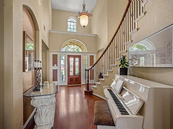 Looking from the foyer back to the front door, you can appreciate the iron railing spiral staircase and two story impressive entry.