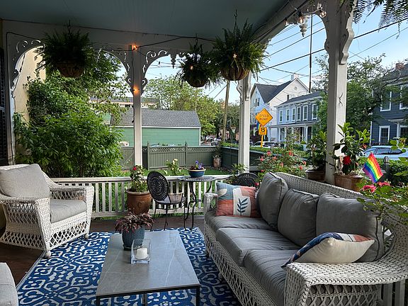 Ceiling fan, wicker furniture, and beautiful landscaping to look at over the yard that stretches half the block including the fenced in yard.