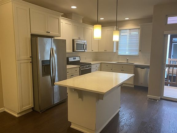 Large Center Island with cabinets and shelves for storage. Bright pendant lamps for excellent lighting.