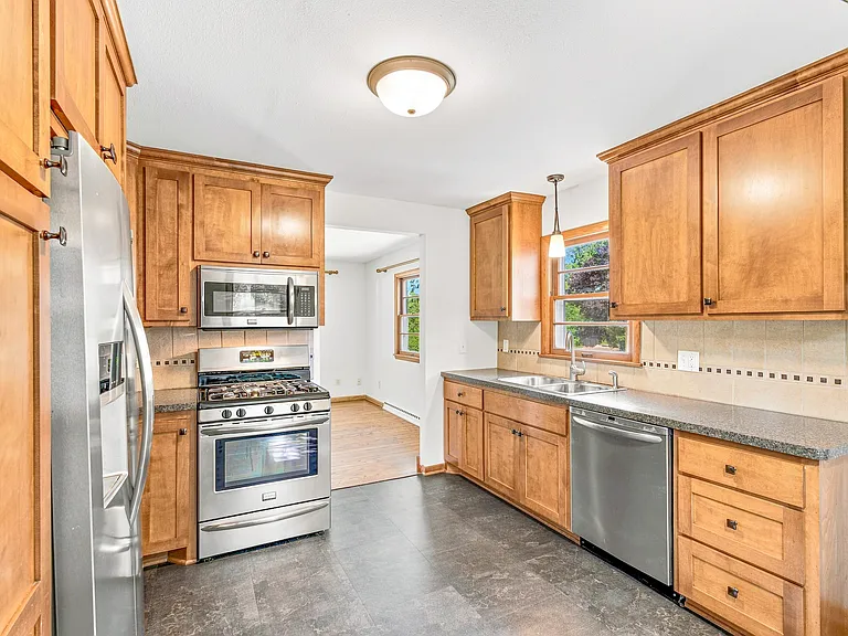 Custom kitchen cabinetry includes large pantry with roll-out shelves, custom backsplash tile, stainless steel appliances