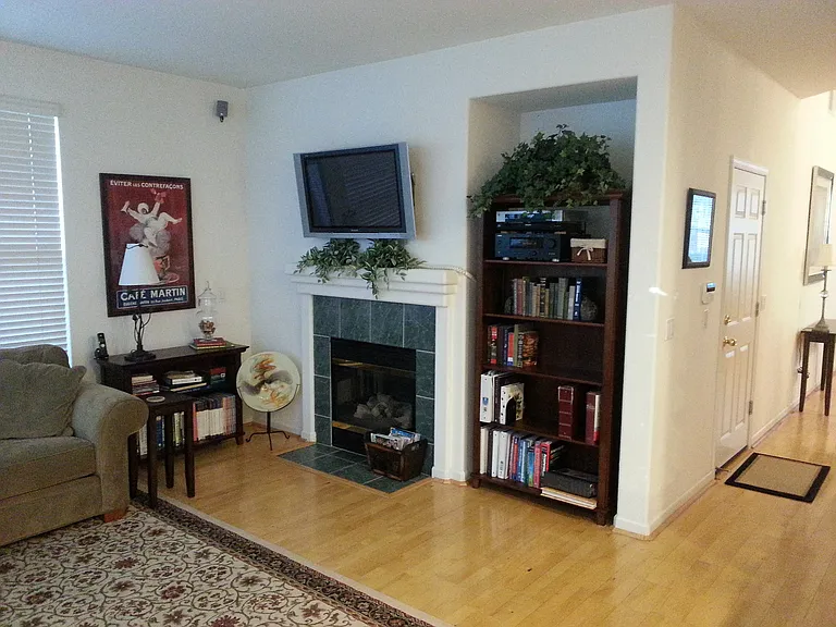 A cozy family room features a beautiful custom tiled fireplace with flat-panel TV-ready wall space above, a recessed alcove for a bookshelf, & warm hardwood floors. A bright hallway seamlessly flows into the front dining & living areas, & door to garage.