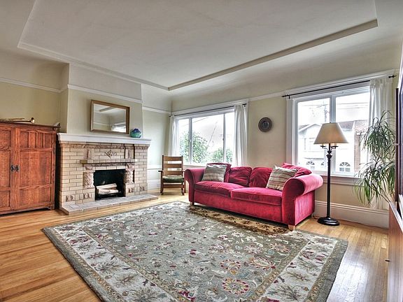 The spacious, bright living room features a wood-burning brick fireplace.