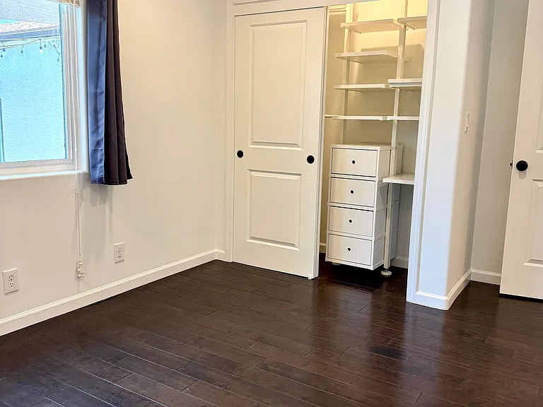 Bedroom 2 with dimmable recessed LED lighting overlooking backyard.