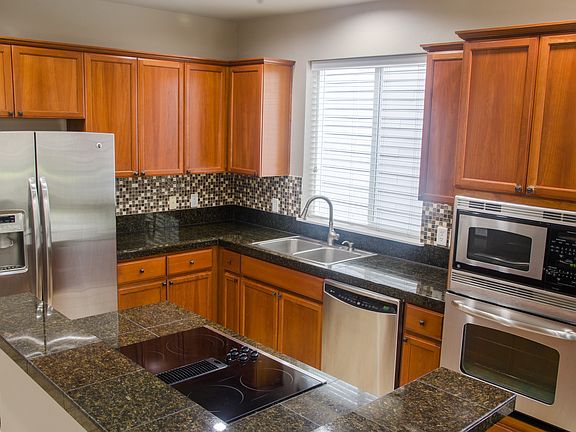 granite countertops, stainless steel appliances, and a sleek glass cooktop with downdraft ventilation