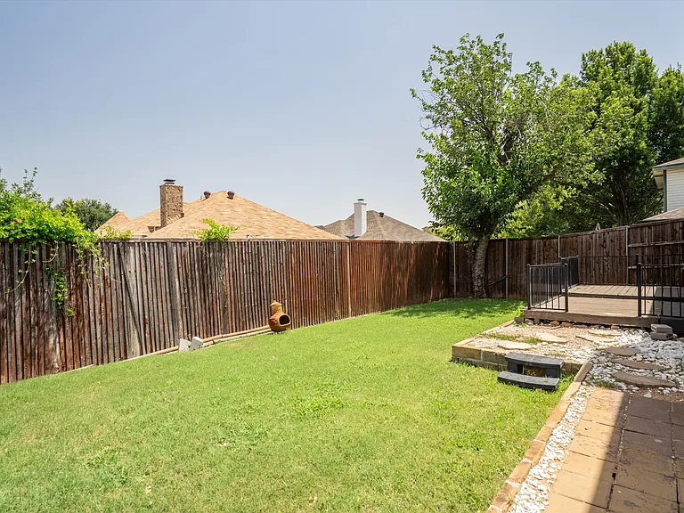 The backyard has some open grassy area for a game of kickball or a small pet.