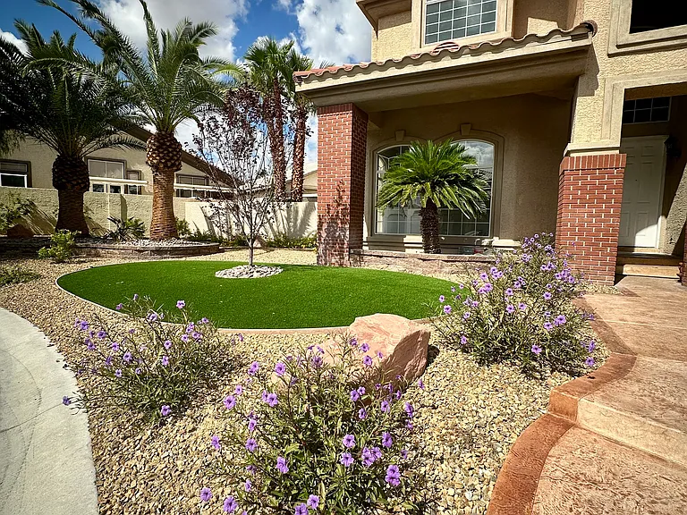 Manicured landscaping with lush turf, mature trees, and desert greenery enhance the home's serene setting.