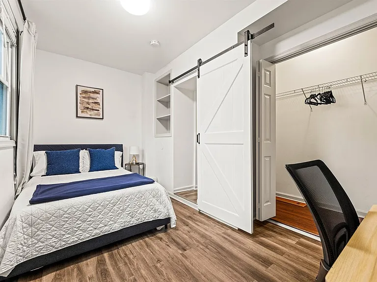 Bedroom with full bed, large window with curtains, built-in shelving, and spacious walk-in closet with barn-door access.