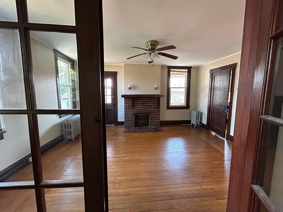 View into living room through dining room. Door to right is front entry door. Door to left of fireplace is for front porch.