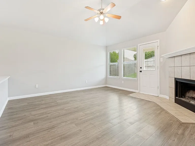 Large open plan living room that has door to backyard and cosy wood burning fireplace.