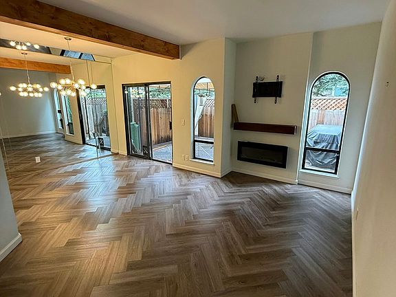 Living room with one wall full mirror wall and entrance to patio.