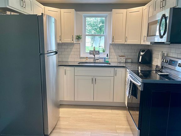 Wraparound kitchen with electric stove/oven, microwave, and full-sized refrigerator.