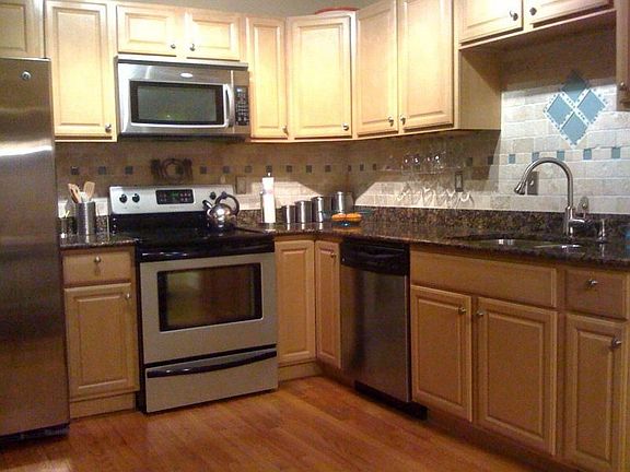 Granite and Stainless Kitchen with Tumbled Travertine and Glass Backsplash