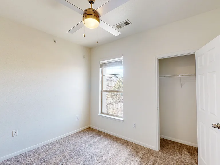 Spacious apartment bedroom with plush carpet flooring.