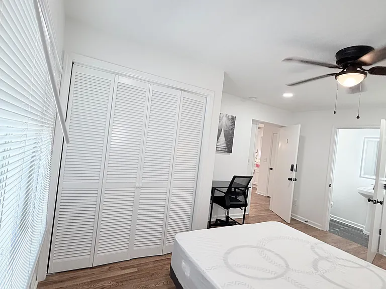 Private bedroom with hardwood floors, ceiling fan, large closet, and a nearby bath, plus space for a desk or seating.