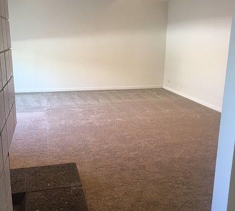 Spacious Living Room (17' x 21') with gas log fireplace. New Carpet. A/C unit. View from Kitchen.