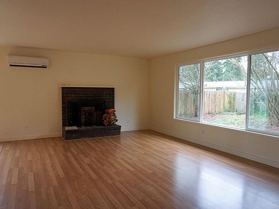 Large living room with wood burning fireplace and picture window looking out over private backyard. Tons of light!