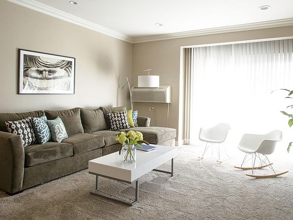 Main living area with air condition unit on farthest wall next to sliding glass door for balcony.