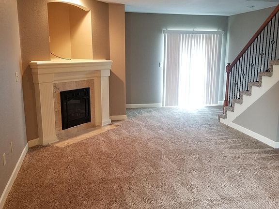 Living room with fireplace, and wrought iron spindles on stairs
