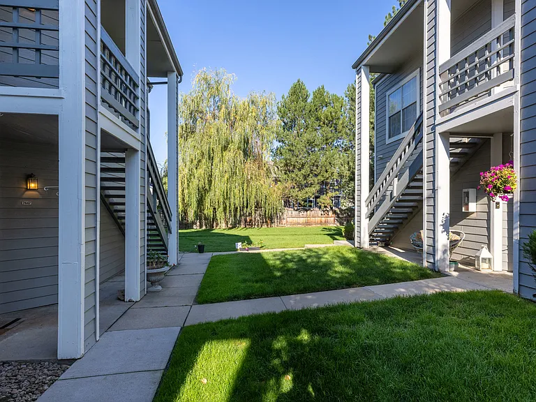Lush community setting with mature trees, green lawns, and generous space between buildings.