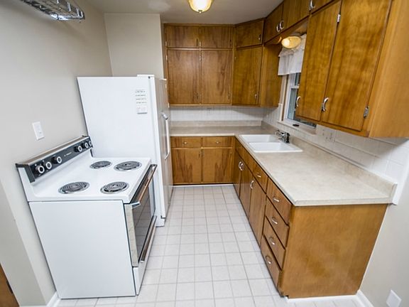The kitchen (9x8) features original wood cabinets which are in impeccable condition and white tile backsplash.  The extra row of cupboards along the ceiling provides additional storage space.  The window over the Kohler sink looks out onto the deck and back yard.