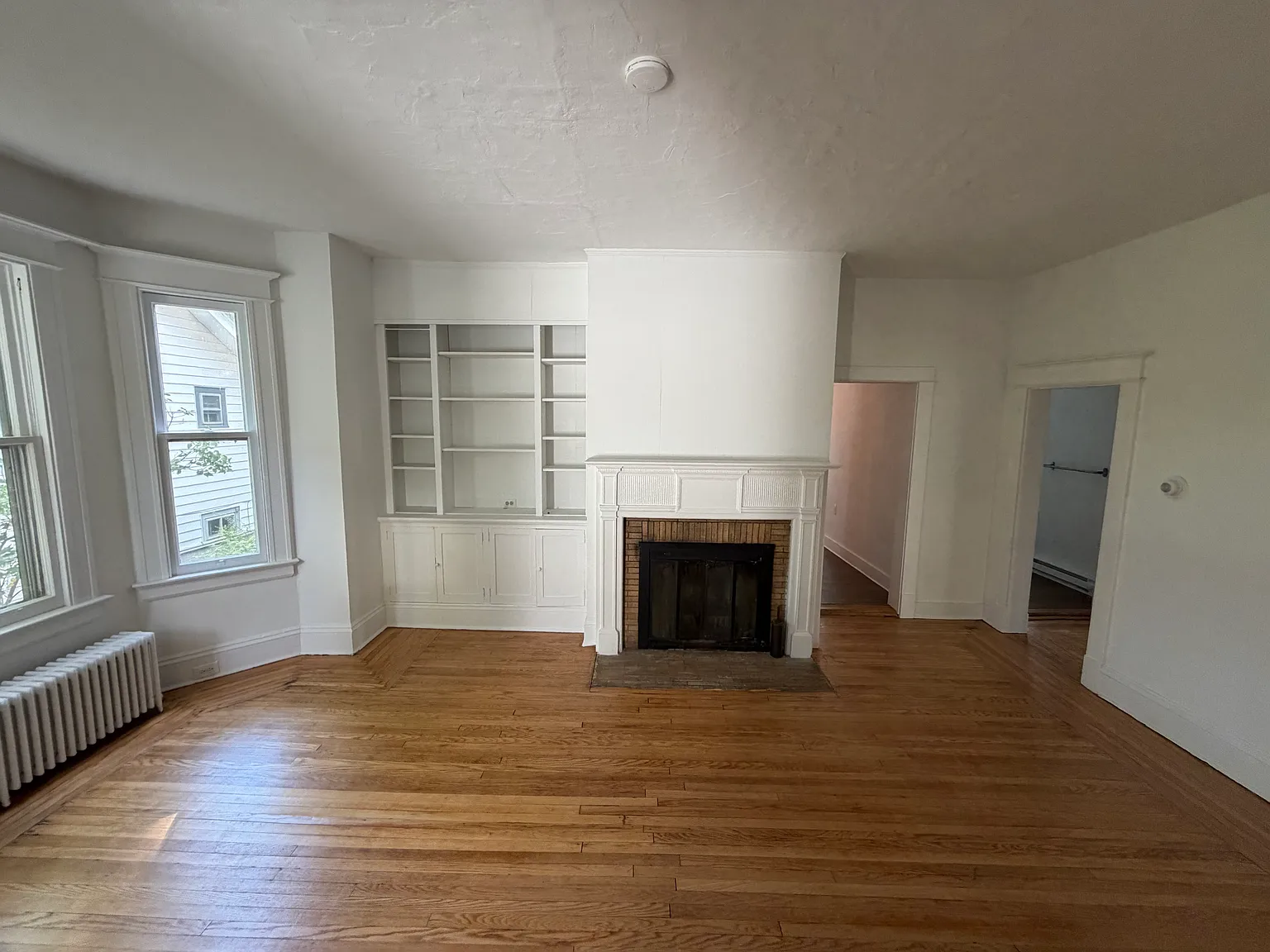 Large living room with bay window, built-in bookcase and cabinets and fireplace (non-functional)