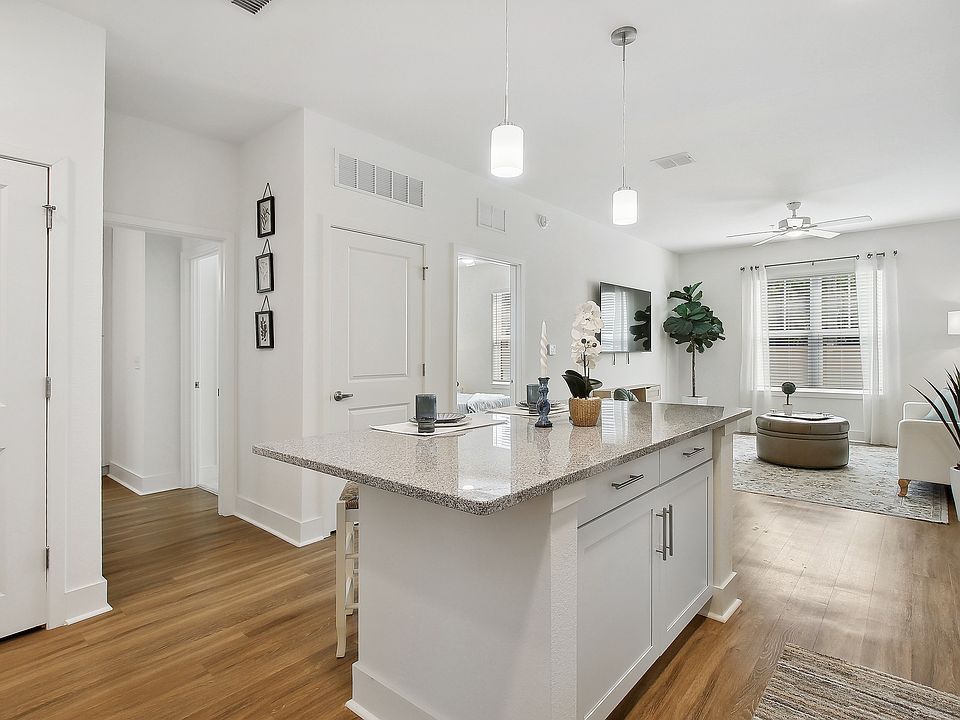 Bright, modern open-concept living space featuring a chic kitchen island, cozy living room with natural light, and elegant wood flooring.