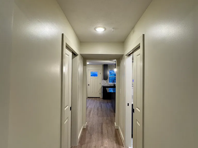 Hallway off the living room with laundry room to the left, half bath to the right, and dining kitchen area and backdoor straight