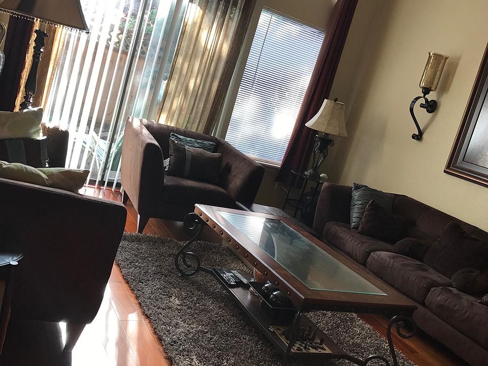 Spacious living room featuring 2-story ceilings, huge windows allowing natural light & beautiful hardwood floors