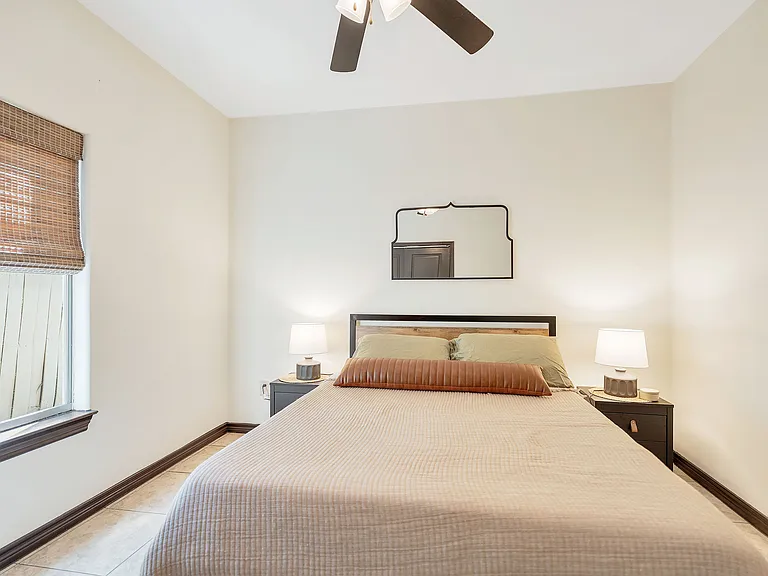 Bedroom interior with a bed, nightstand, and ceiling fan, located in La Joya Apartments, Laredo, Texas