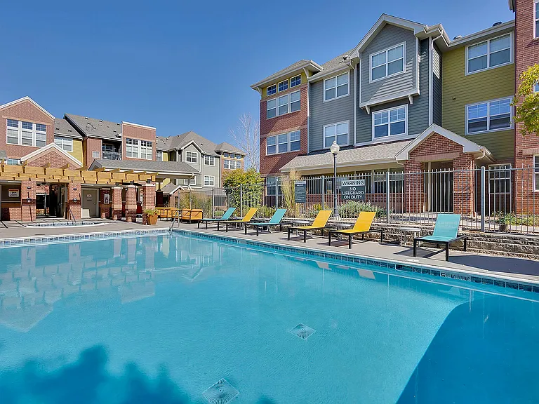 Charming apartment complex featuring a refreshing swimming pool surrounded by colorful lounge chairs and modern architecture.