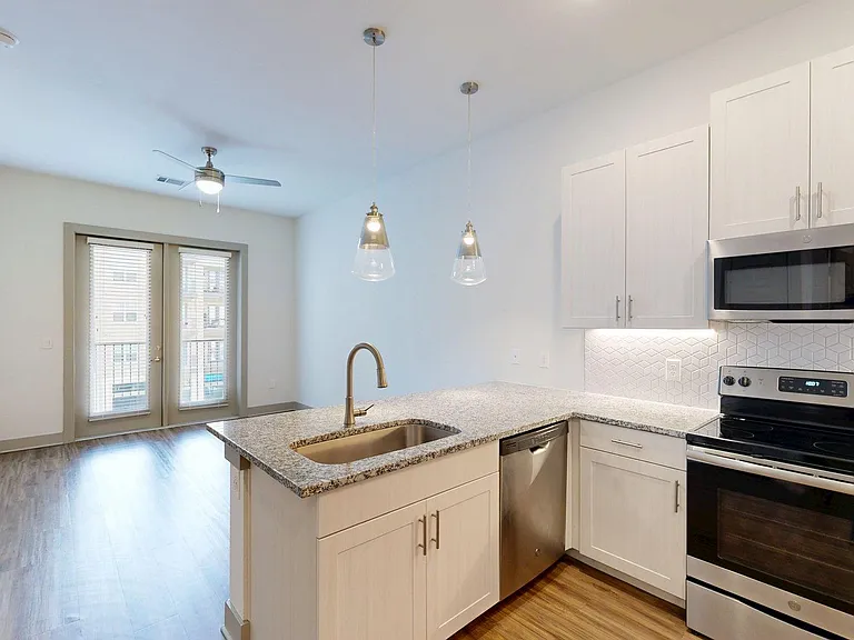Apartment Kitchen with Stainless Steel Appliances, Dining and Living Room with Wood-Style Flooring.