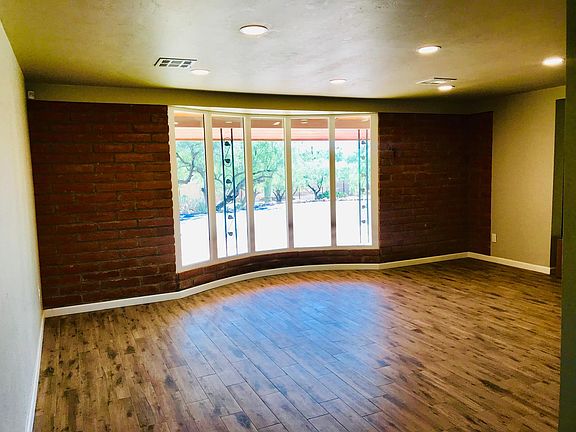 Grand room features beautiful arched window overlooking desert and a beautiful adobe brick accent wall. The recessed lighting is perfect any time of day or night!