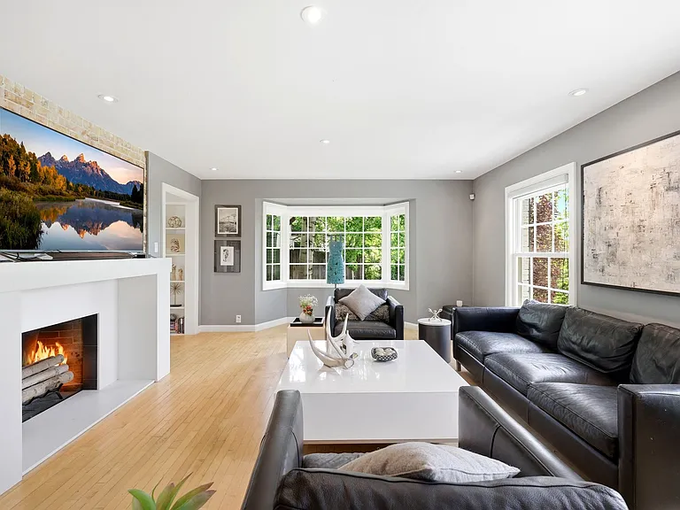 Main living room with tons of windows, built in shelving, and cozy fireplace.