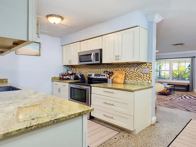 Open kitchen with granite counters, ample cabinetry, and stainless appliances, flowing into the main living area.