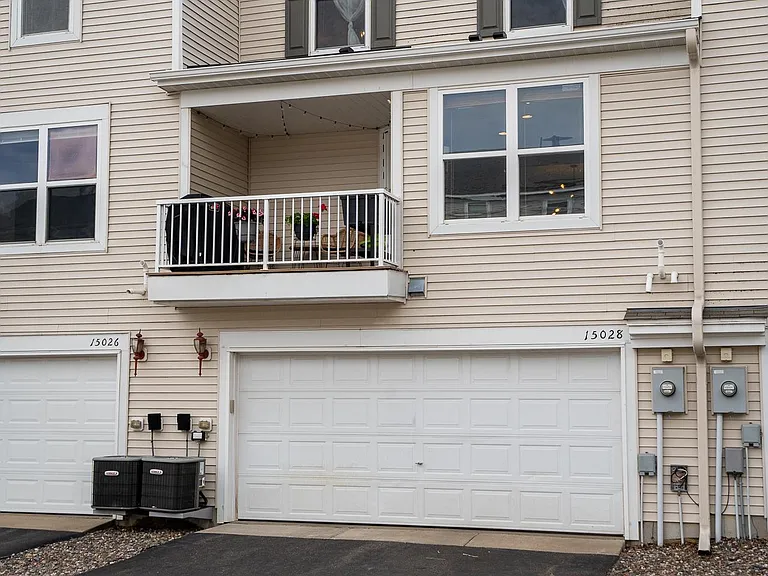 north side view of garage and entrance into the lower floor. top floor windows from 2nd bedroom (on right) and loft space (on left).