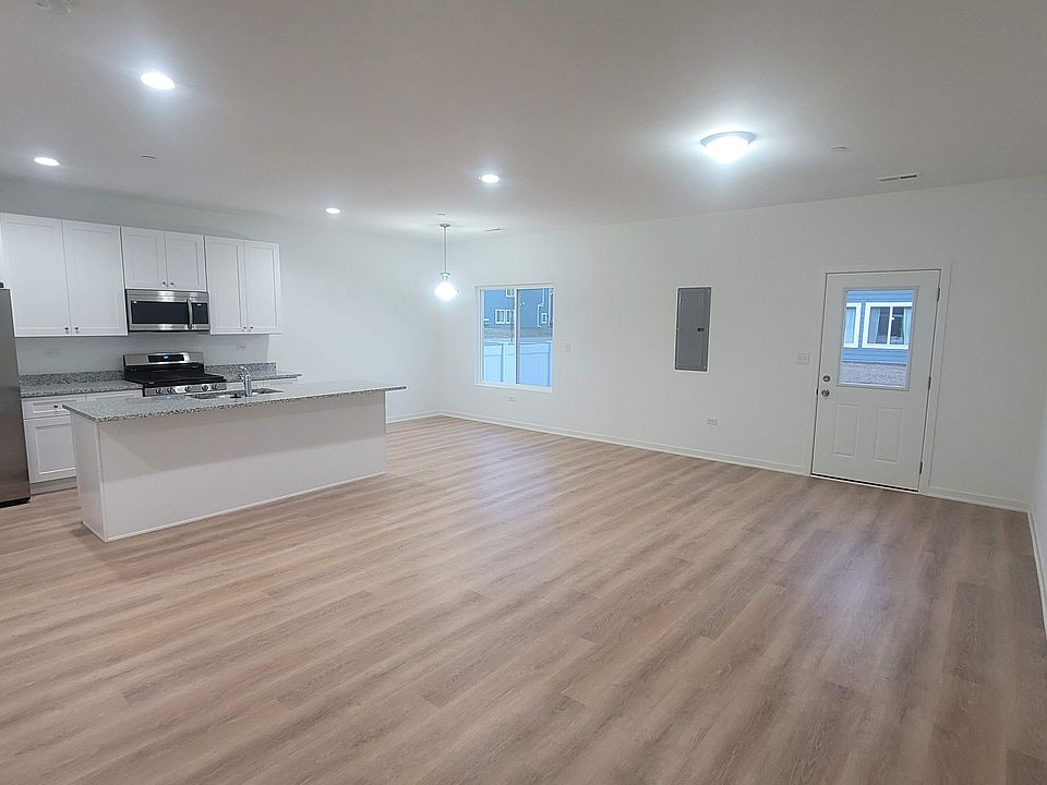 Great Room. kitchen equipped with stainless steel appliances, Granite countertop island with large steel sink. Ahead to the left is the dining area, while the living space is on the right, offering access to the backyard.