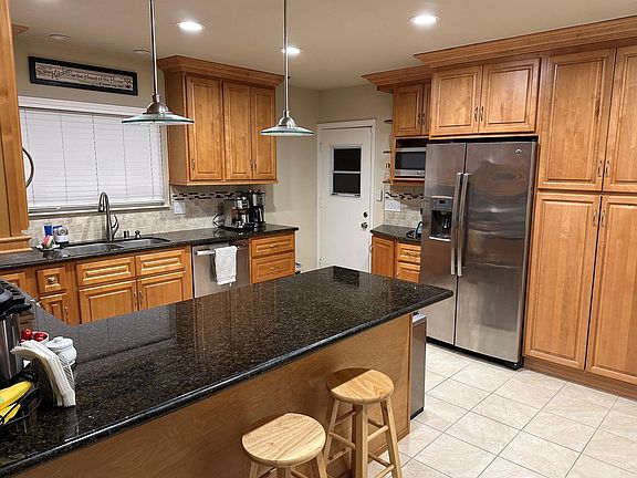 Different angle of kitchen showing microwave, refrigerator, and pantry closet to the right of the fridge.