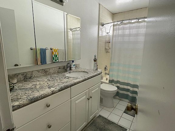 Upstairs full bathroom with tub/shower. A glass shower door enclosure may replace the shower curtain. Granite countertop and mirrored medicine cabinet doors shown.